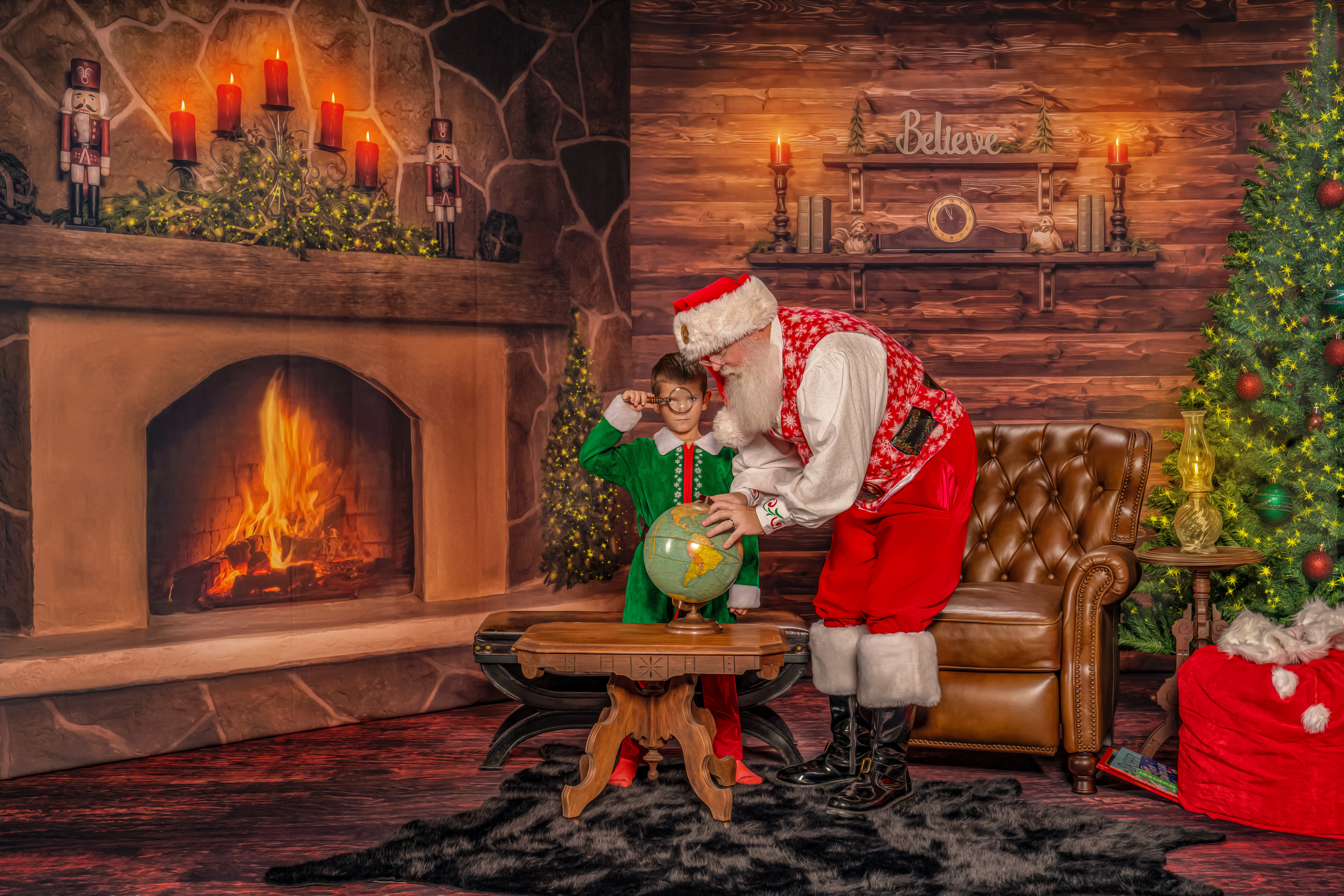Jingle the Elf stares throught the magnifying class while Santa George shows him where the North Pole is creating Christmas memories during The Magic of Santa experience