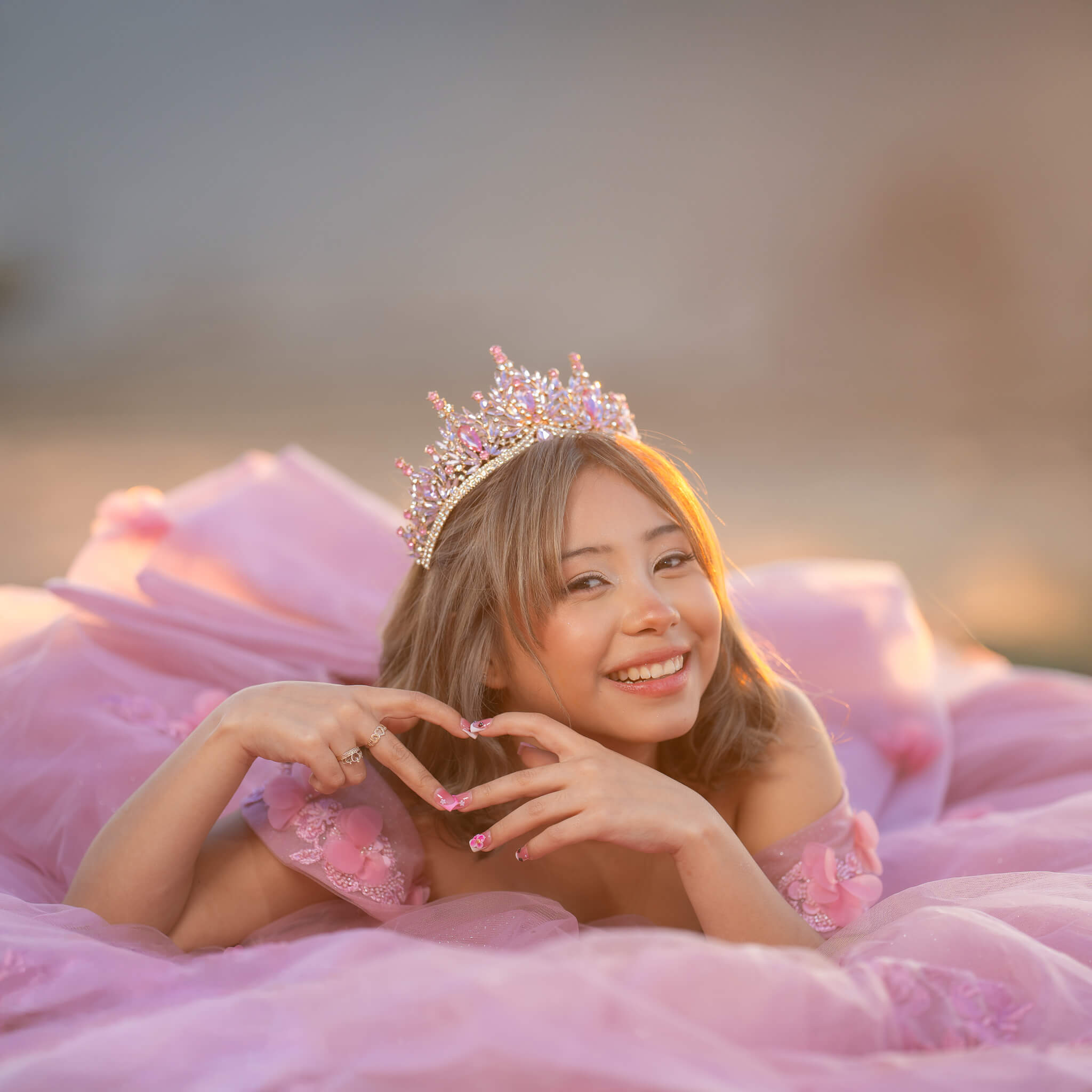 Quinceañera sonriendo con corona y vestido rosa durante su sesión