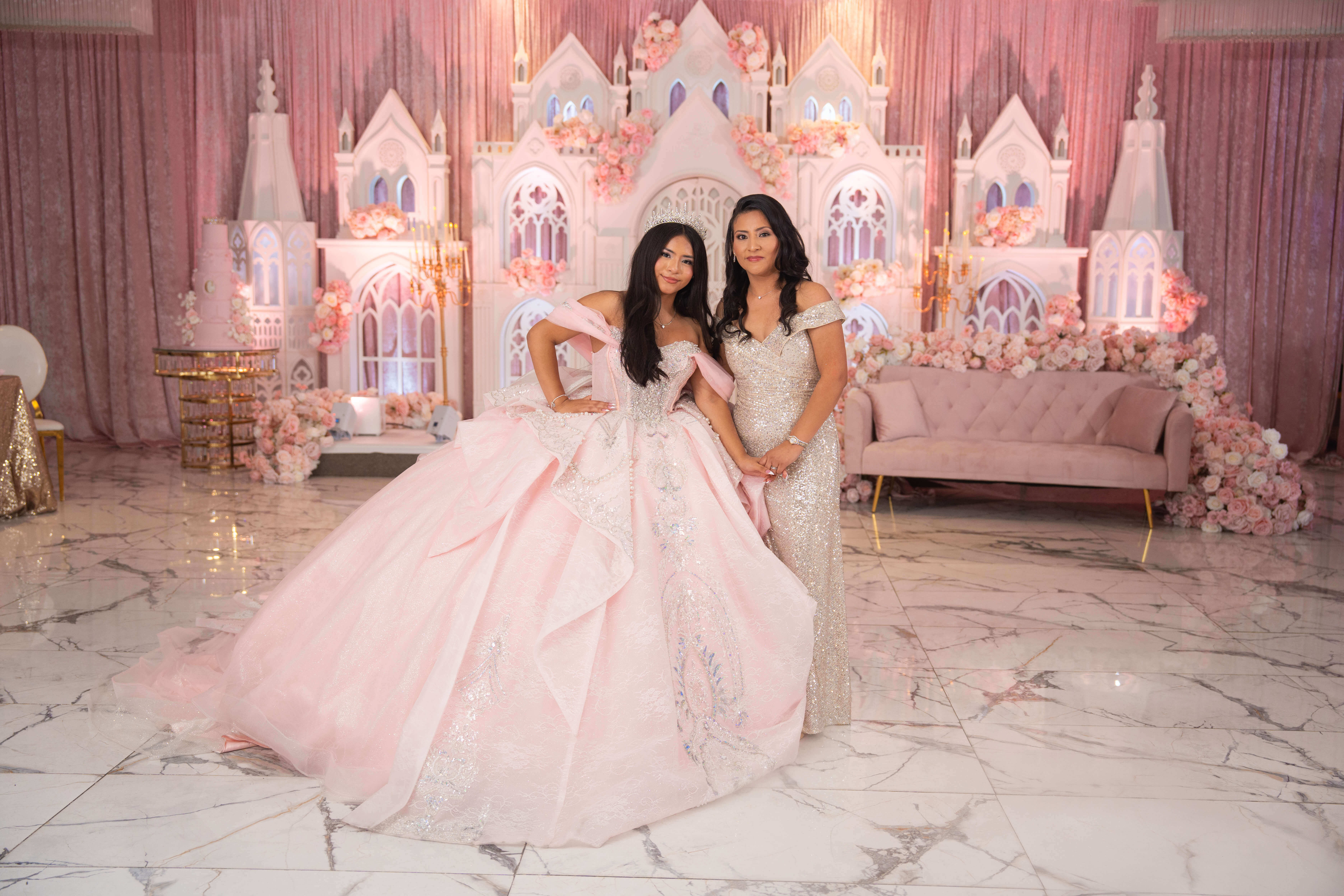 Quinceañera abrazada a una invitada especial frente a la decoración