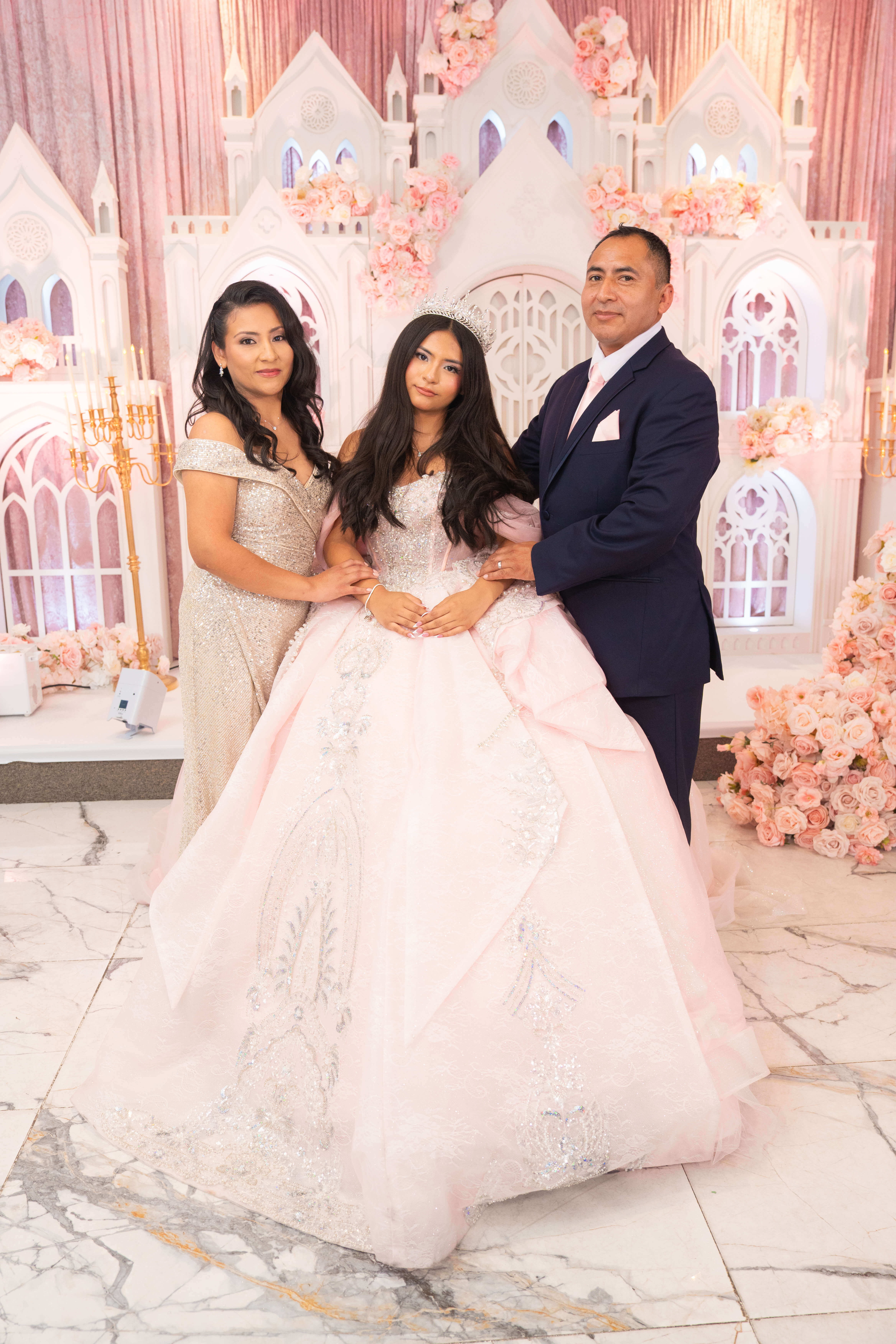 Quinceañera con su mamá y su papá en el salón de su fiesta