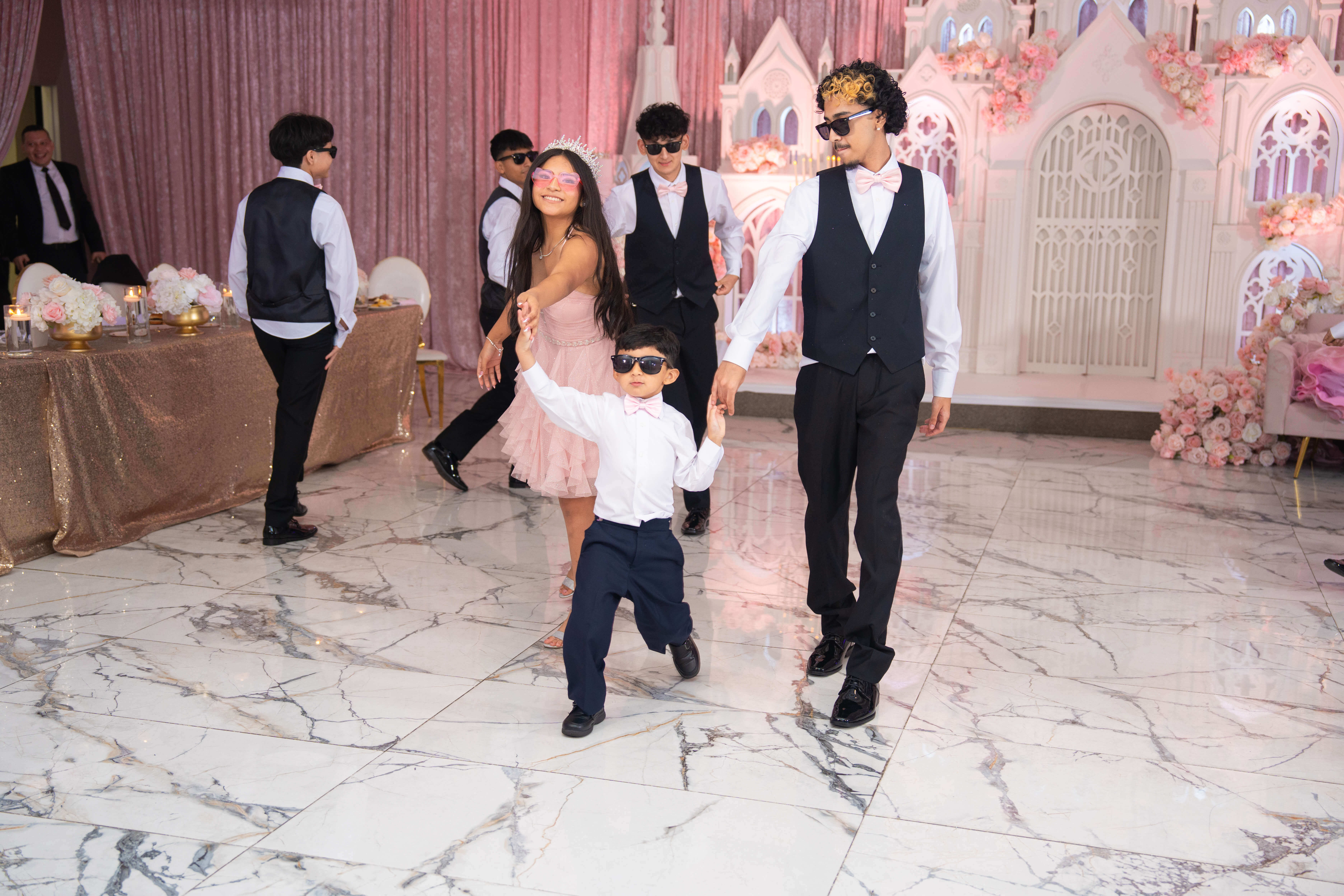 Quinceañera bailando con sus chambelanes en la pista
