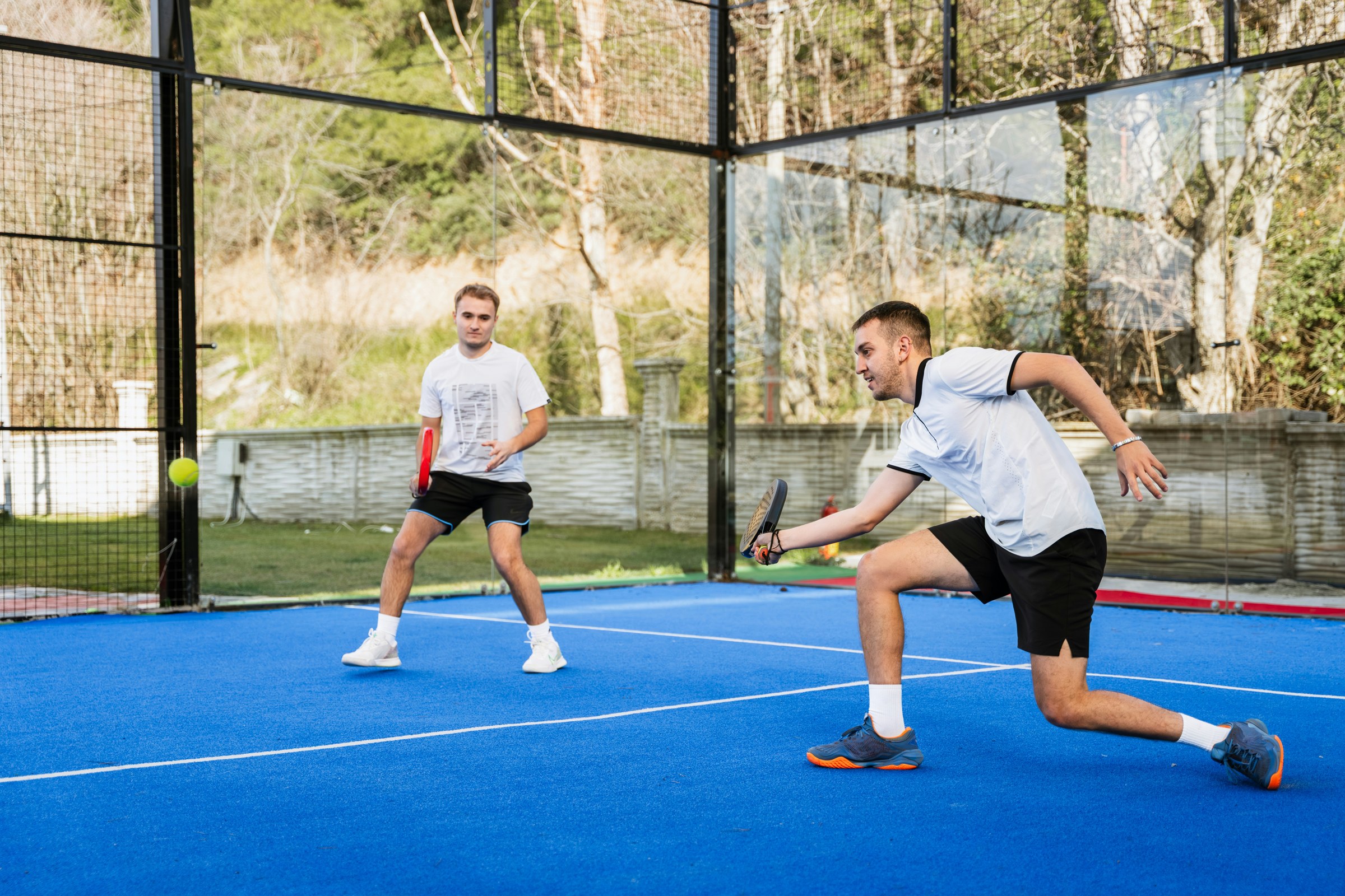 Players rallying on an outdoor blue padel court