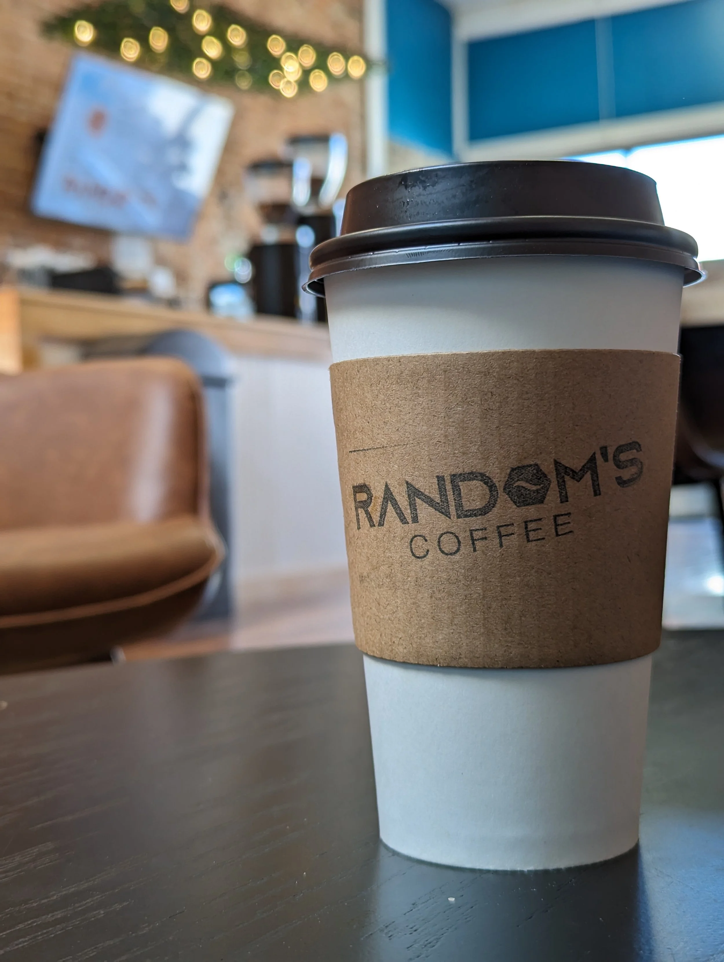 Picture of a coffee cup with sleeve and Random's Coffee brand 