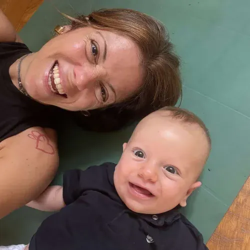 Giovi sorridente sul tappetino accanto al suo bimbo