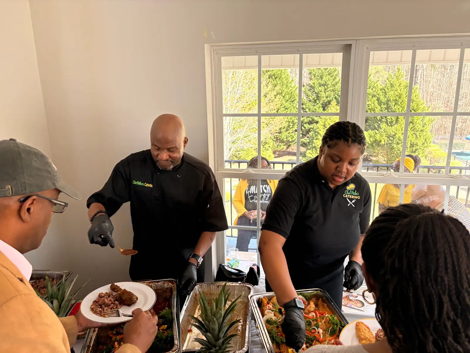 Chef Mike's Catering team member serving a steaming tray at an event