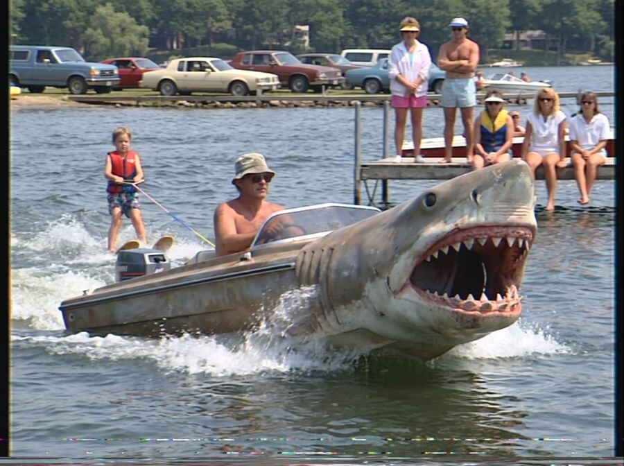A man water-skiing behind a shark that is also a speedboat