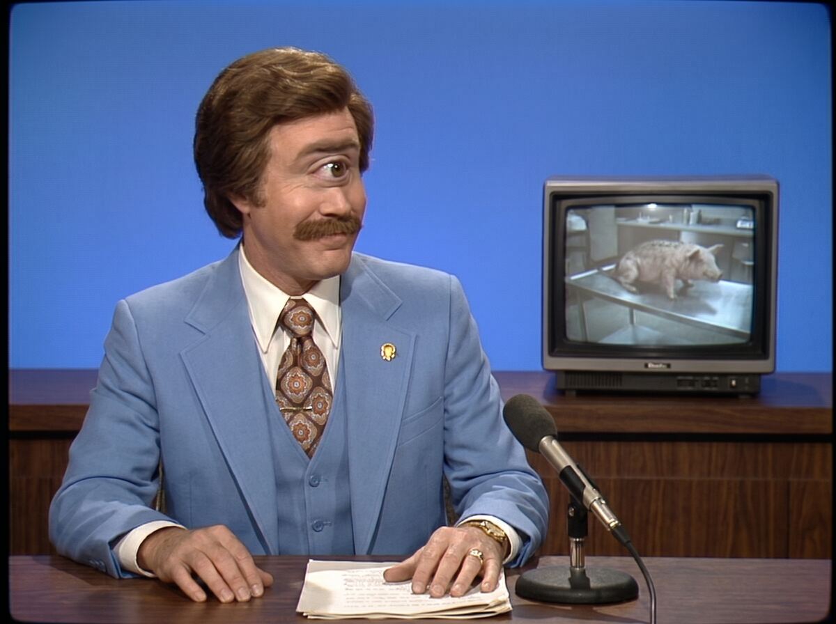 Chet at the desk with a pig on the monitor behind him