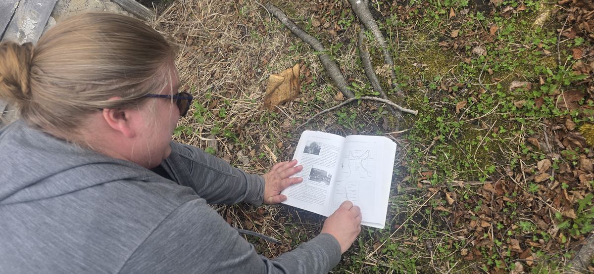 Emily Macgillivray reading a historical field guide outdoors while researching a Lake Superior route