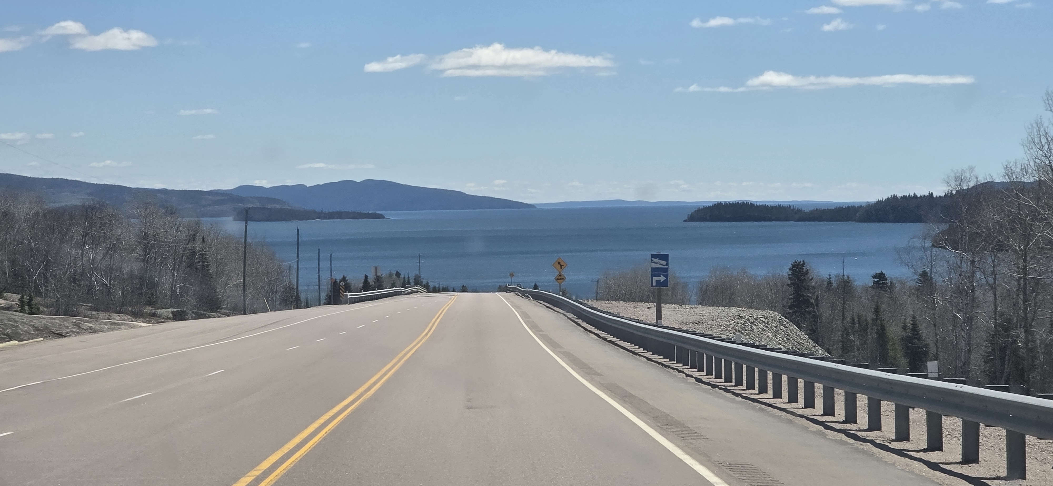A two-lane highway descending toward Lake Superior, framed by forested hills