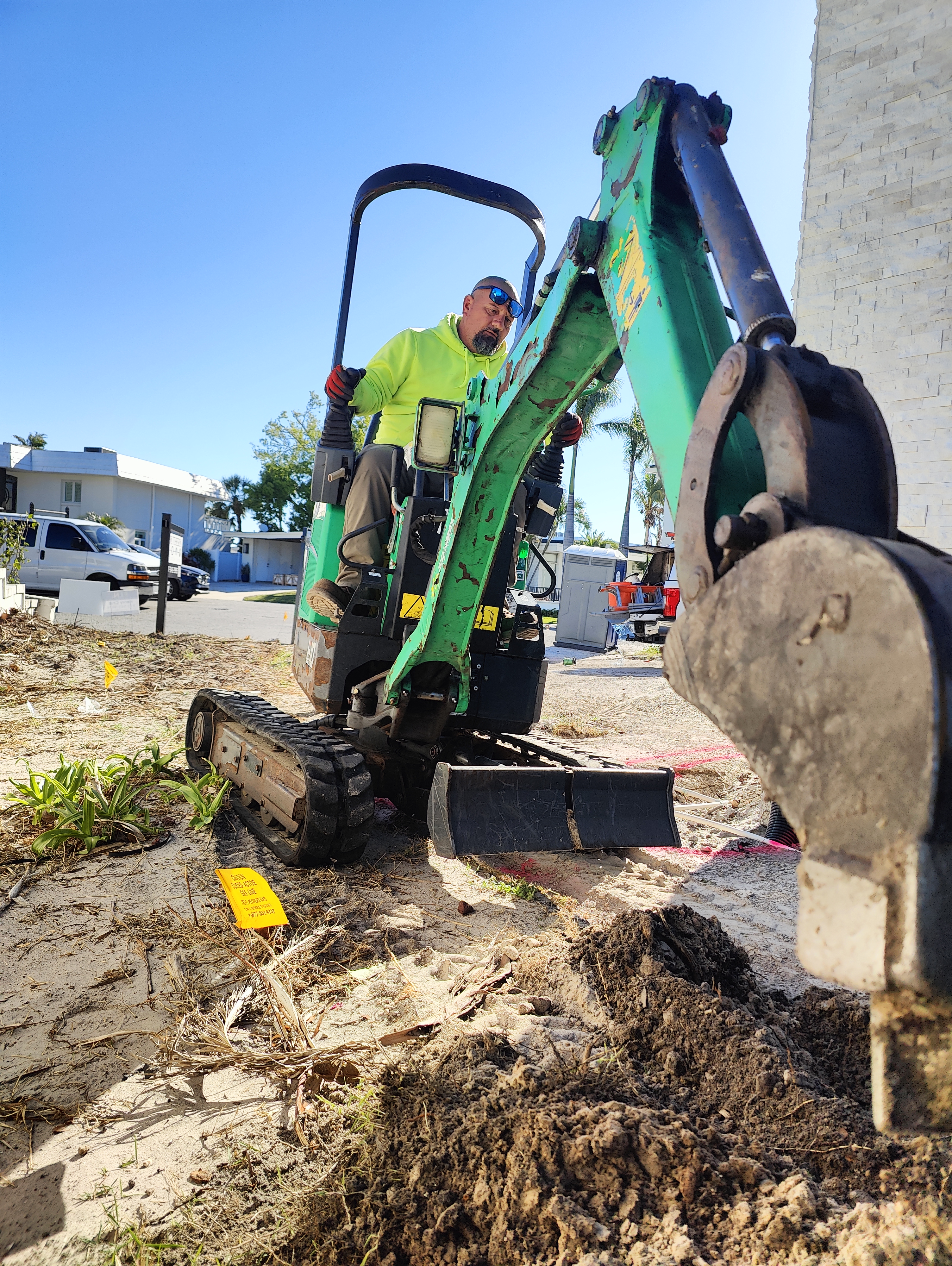 Trufam crew installing an underground drainage system with an excavator in Tampa Bay