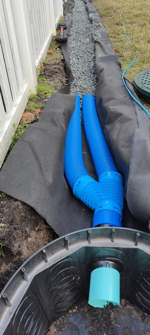 Two four-inch perforated pipes running side by side in a fabric lined French drain trench on a Tampa Bay job