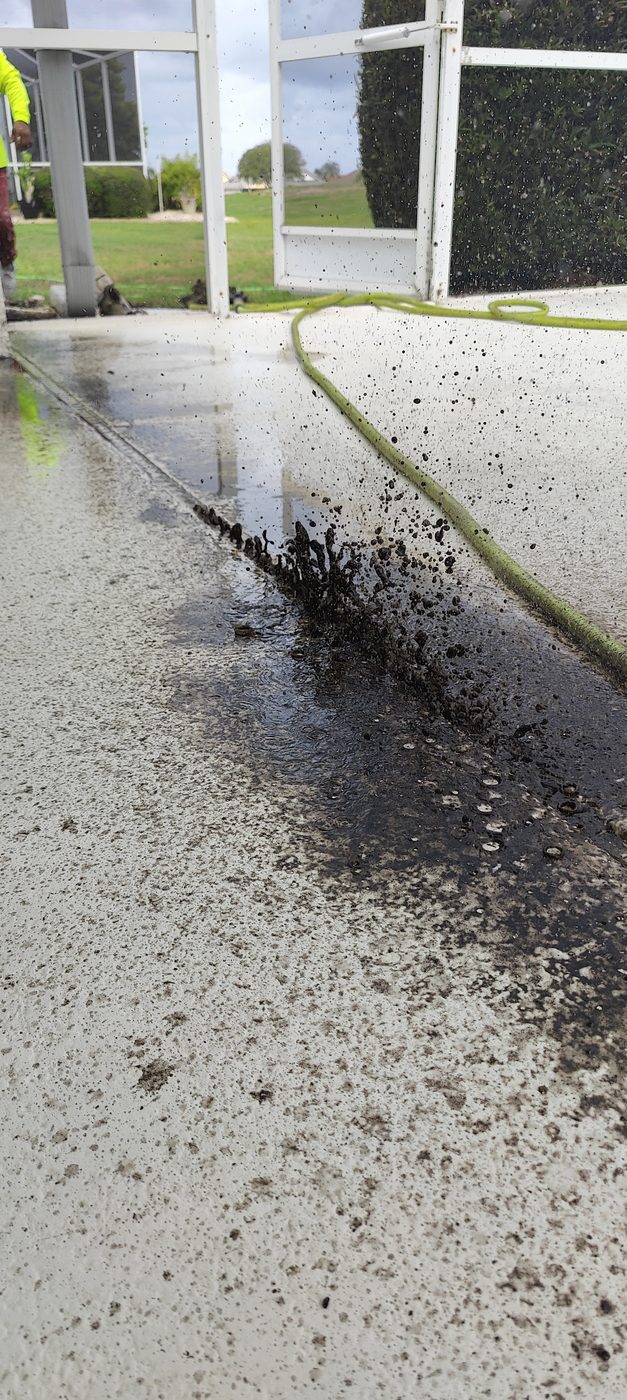 Trufam hydro jetting a pool deck channel drain in Tampa Bay with years of packed debris blasting out of the drain slot