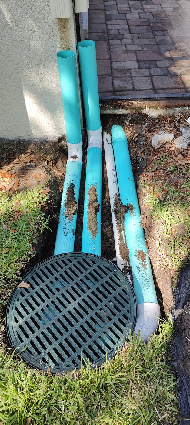 Grated catch basin set flush at a low spot with solid drainage lines feeding it