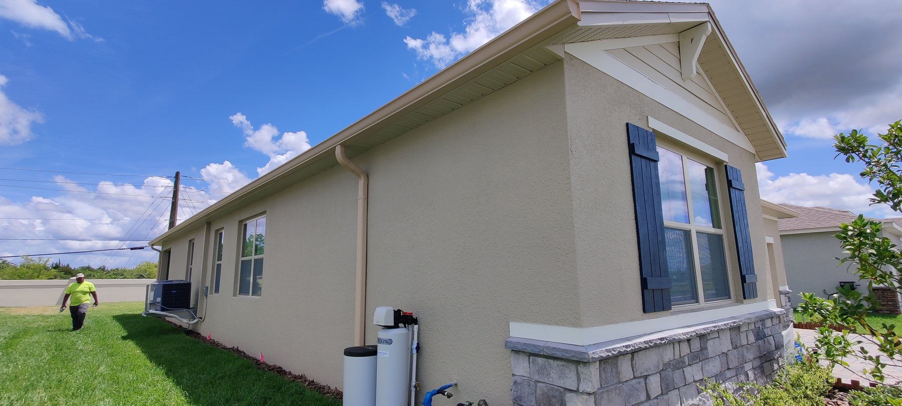 Side of a tan single-family Tampa Bay home with a clean gutter and downspout by Trufam Drainage