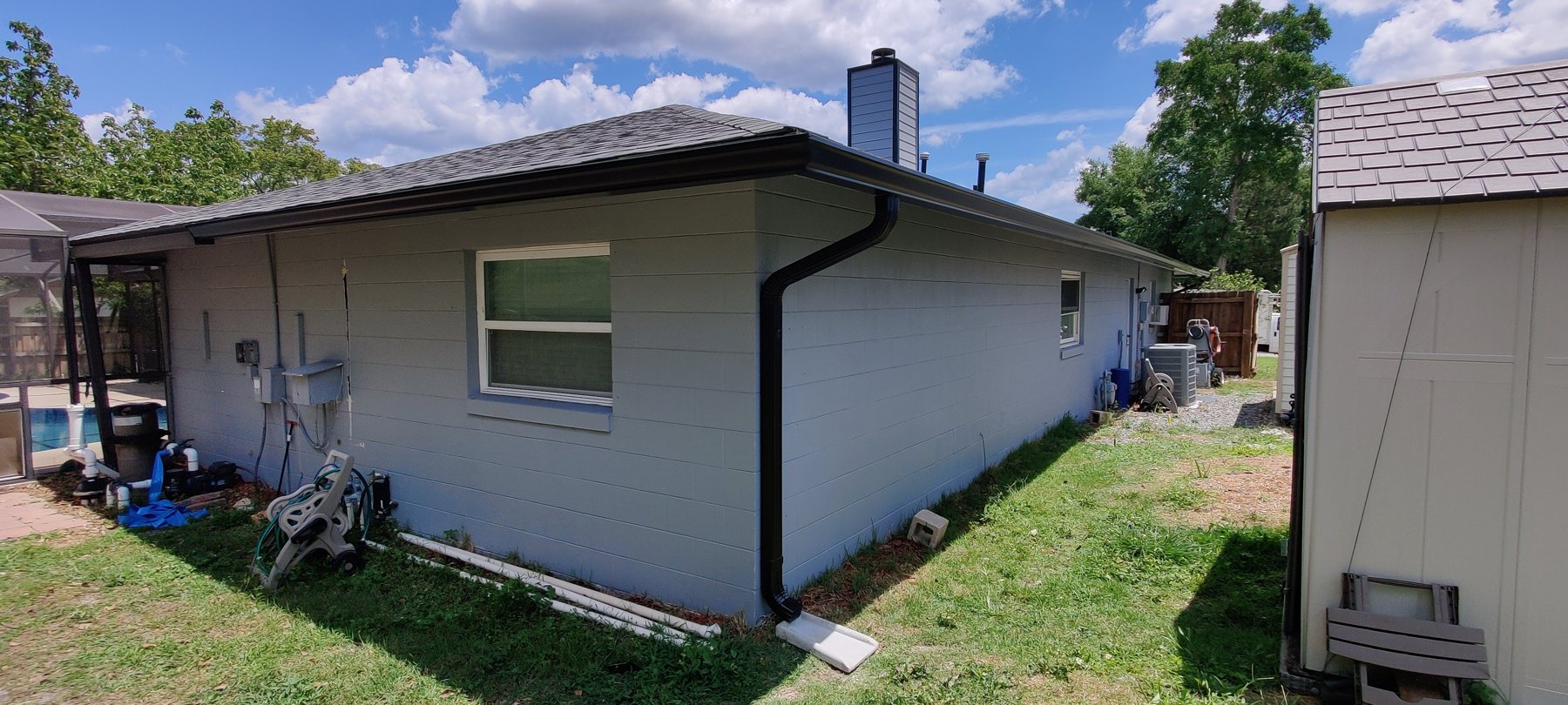 Single-family Tampa Bay home with a pool cage and a clean gutter line by Trufam Drainage