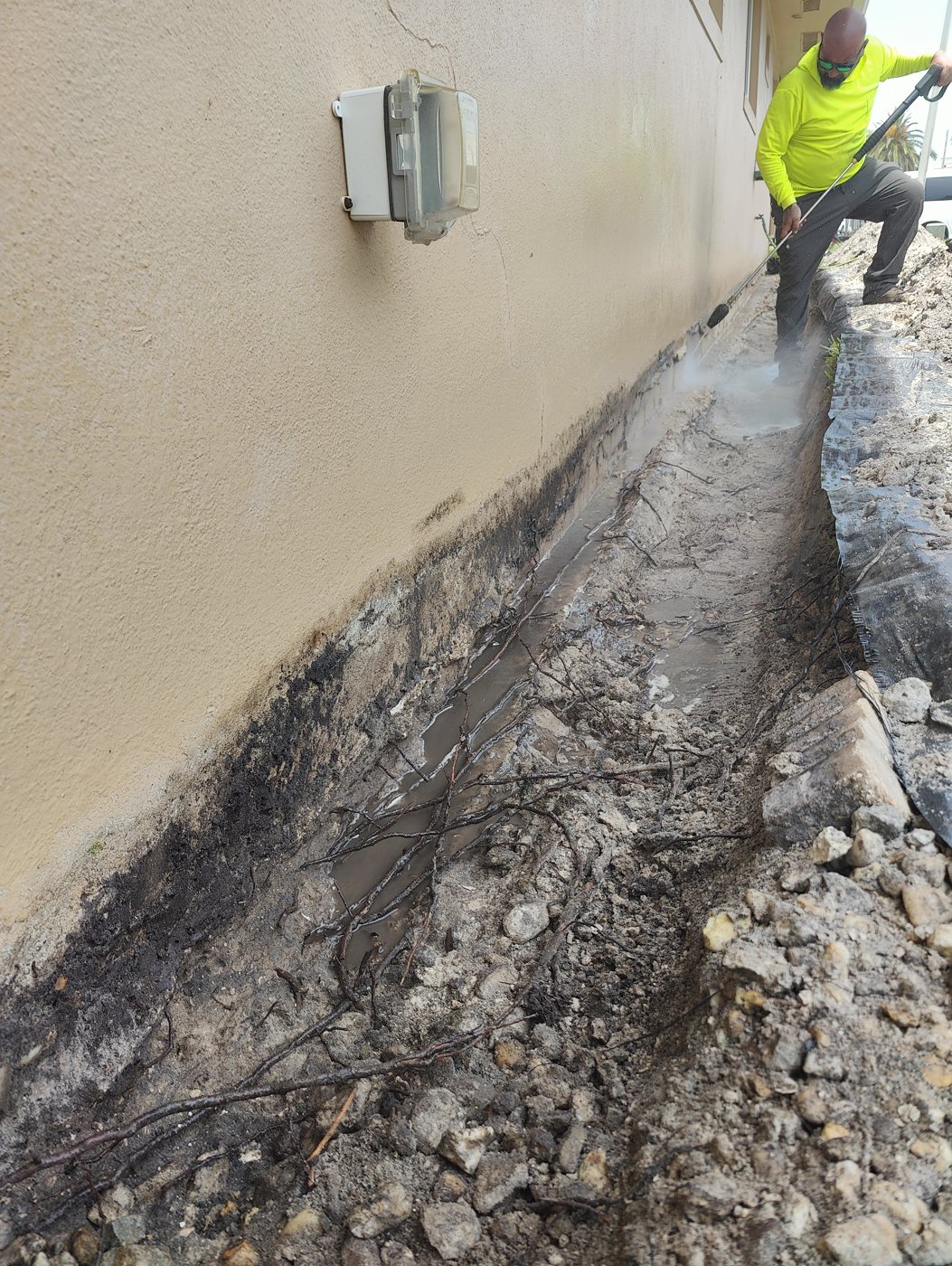 Trufam crew cleaning a foundation wall with a commercial pressure washer to prep it for waterproofing coating in Tampa Bay