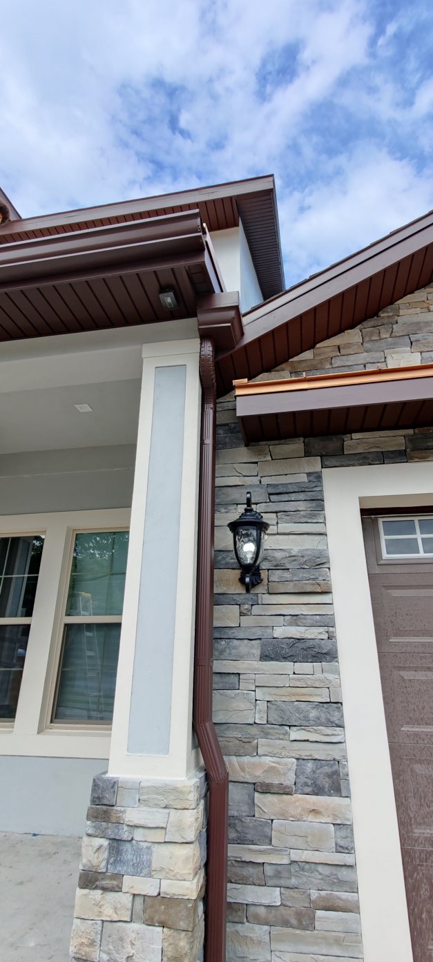 Custom Trufam leader head collecting the gutter run beside a stone accent column on a Tampa Bay home