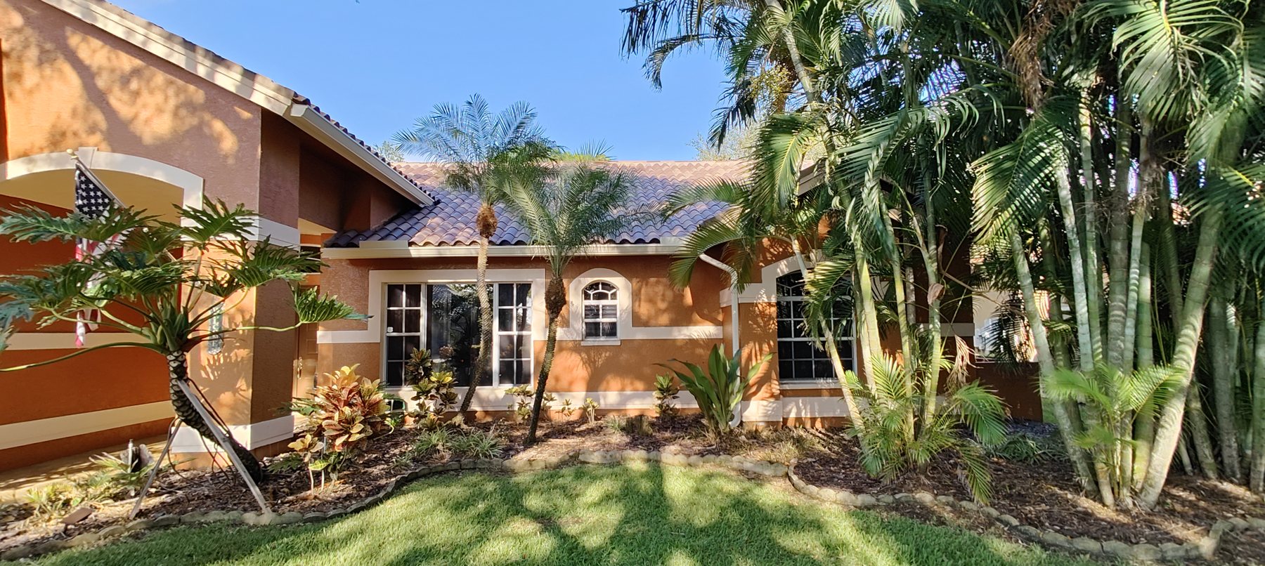 Tampa Bay tile-roof home framed by palms, gutters and guards by Trufam Drainage