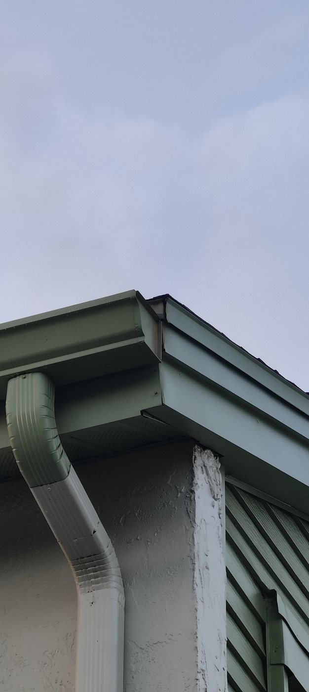 A hand-cut and sealed seamless gutter corner with the downspout outlet on a Tampa Bay home