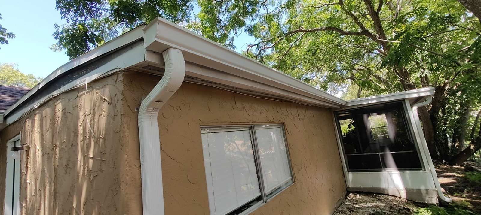 A new white seamless downspout running down a Tampa Bay home to carry roof water away from the foundation