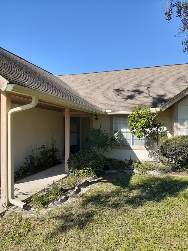White seamless gutters wrapping the corner of a single-story Tampa Bay home with the downspout