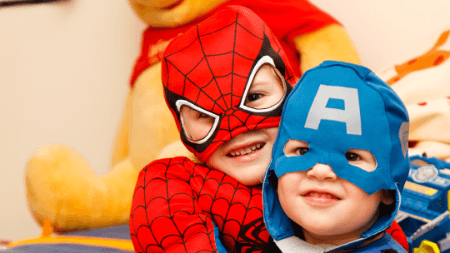 Two young boys dressed up in superhero costumes and playing after an eye exam in Sherwood Park