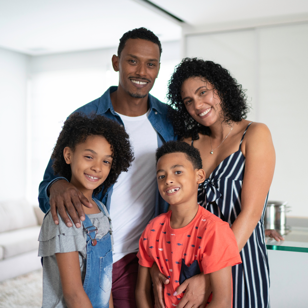 Familia hispana multigeneracional sonriendo frente a una casa residencial estilo Ontario