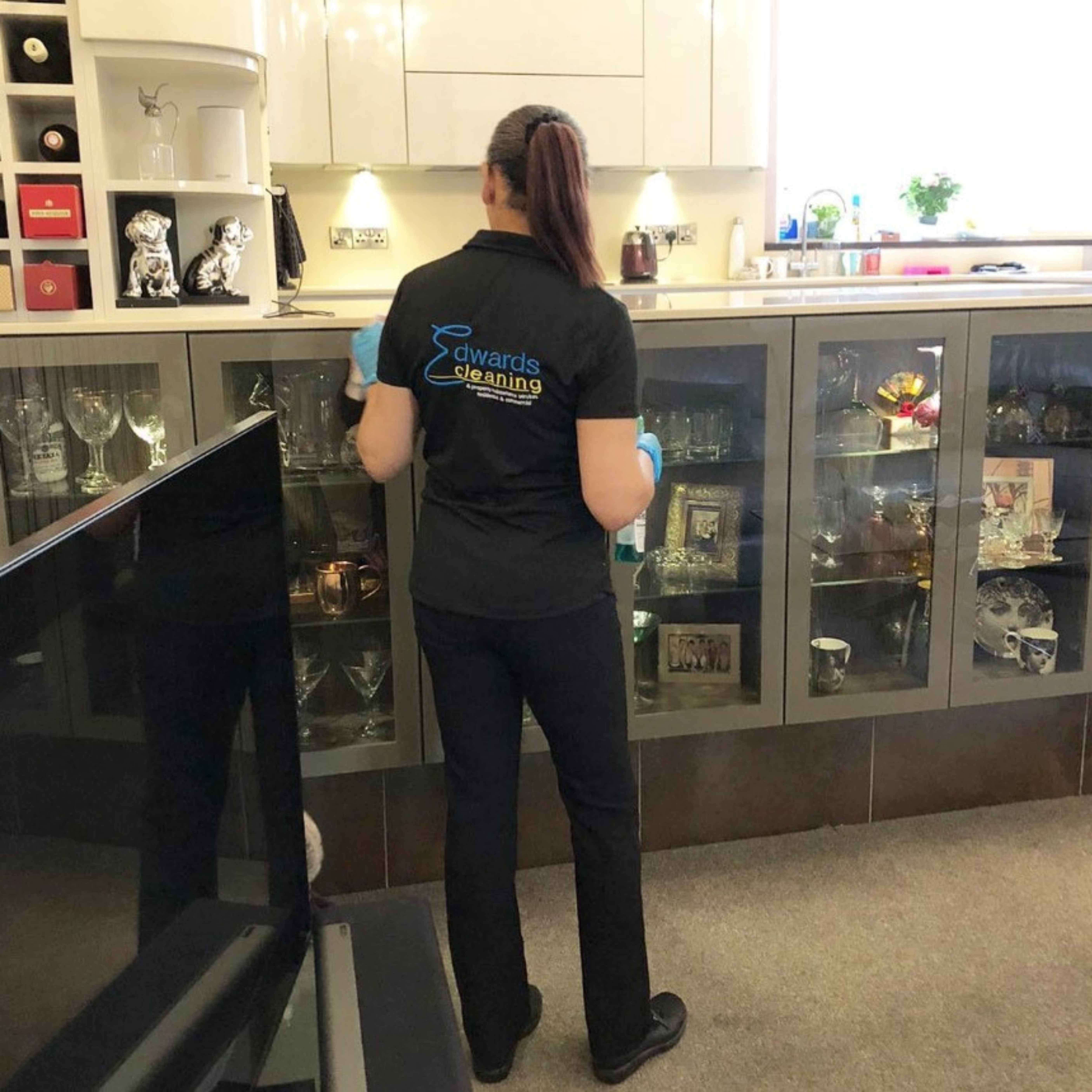 Residential cleaner from Edwards Cleaning dusting and polishing a living room cabinet in a Nottingham home