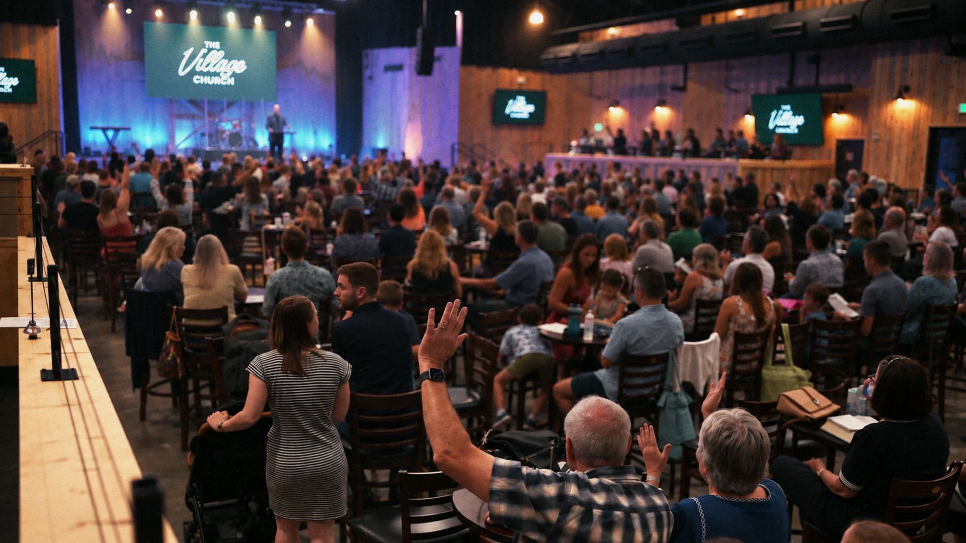 People worshiping with hands raised during a Sunday gathering at The Village Church