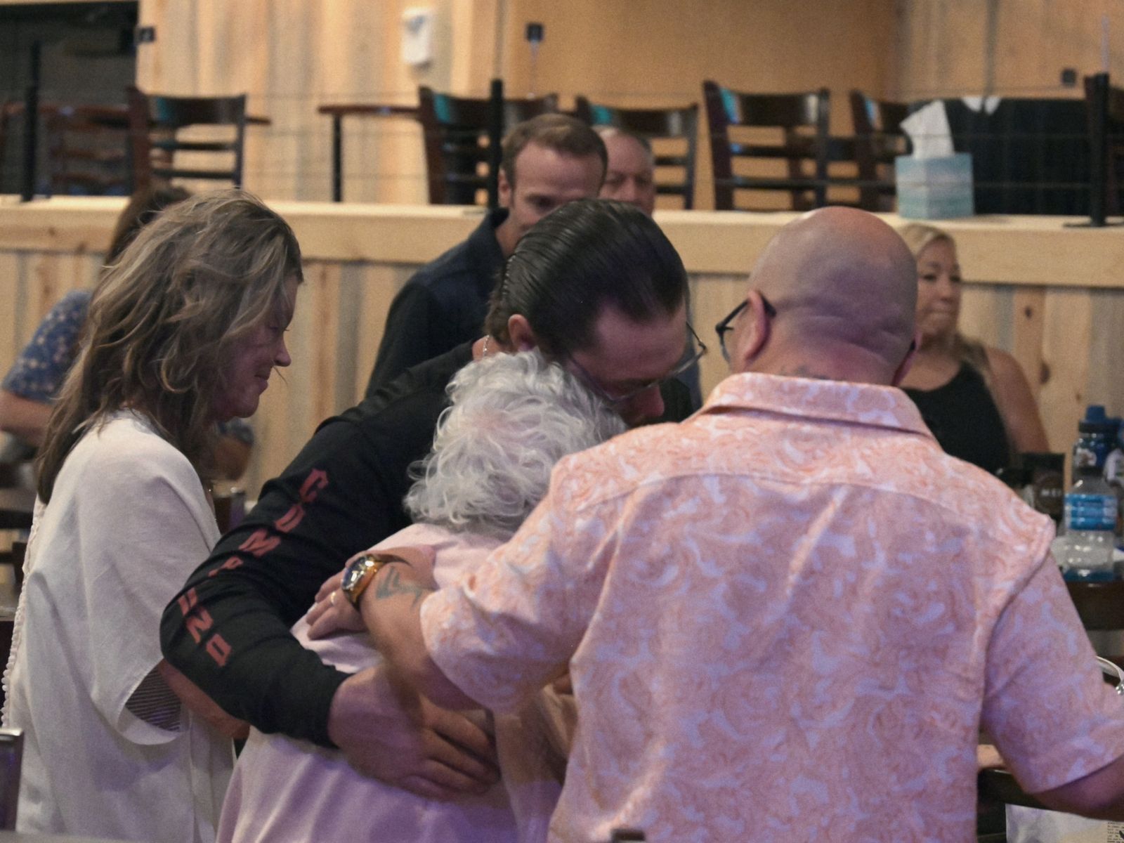 Friends gathered around an older woman, praying with her at a Sunday gathering