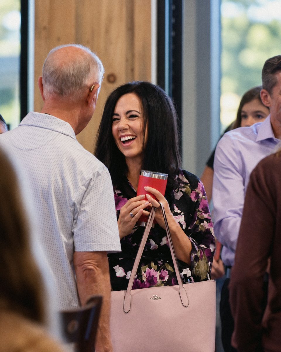 A woman laughing in conversation with friends before a Sunday gathering