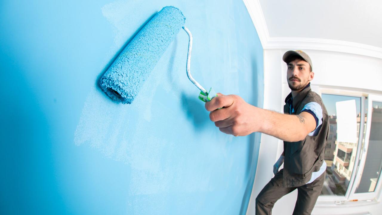 man painting home office  blue with roller