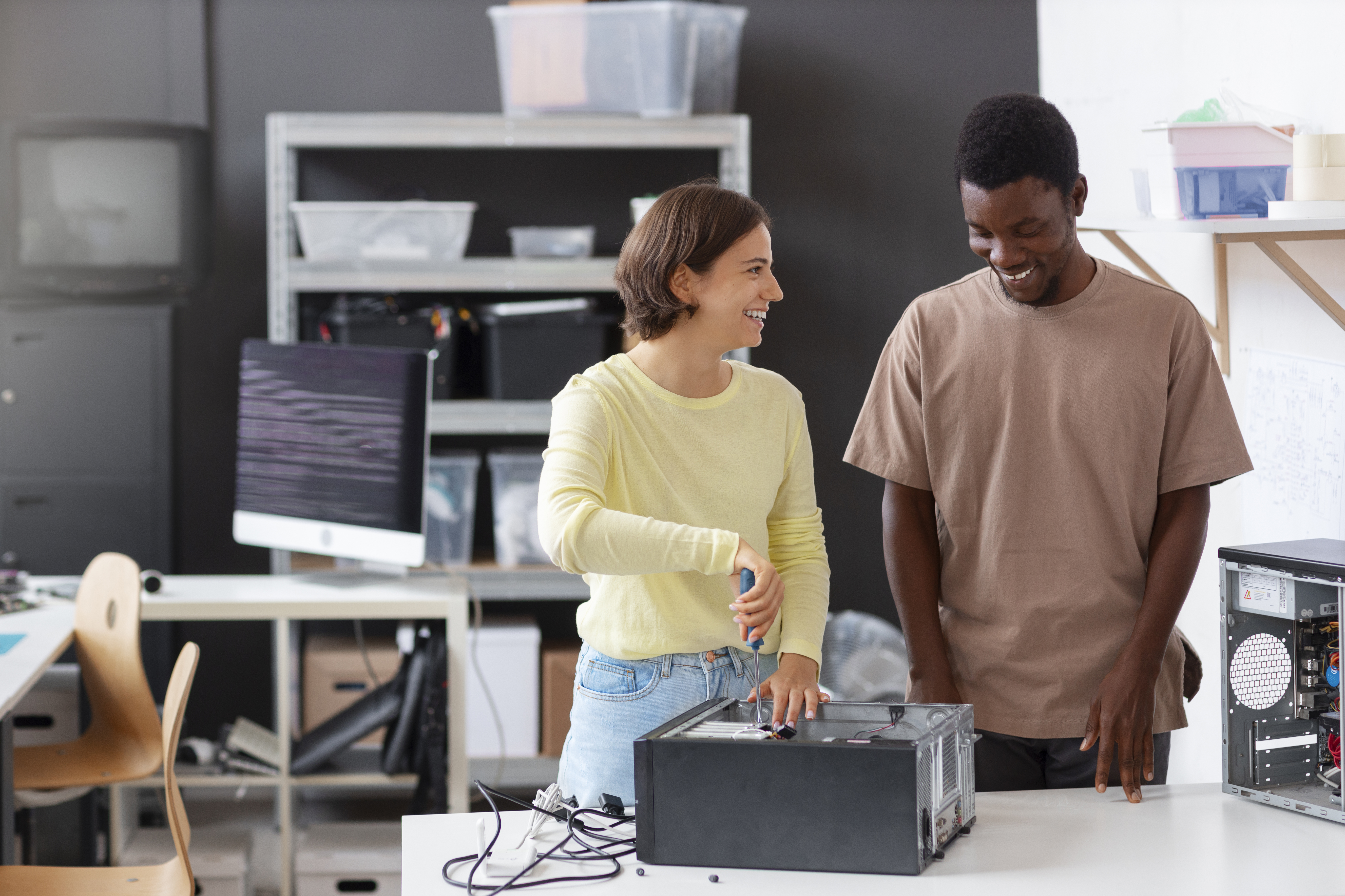 A close-up view of two technical professionals collaboratively working on a disassembled computer motherboard at an electronics workstation. This represents Heartfelt IT's skilled IT Volunteer Program, hands-on hardware repair, and pro bono infrastructure troubleshooting for Ontario nonprofits.