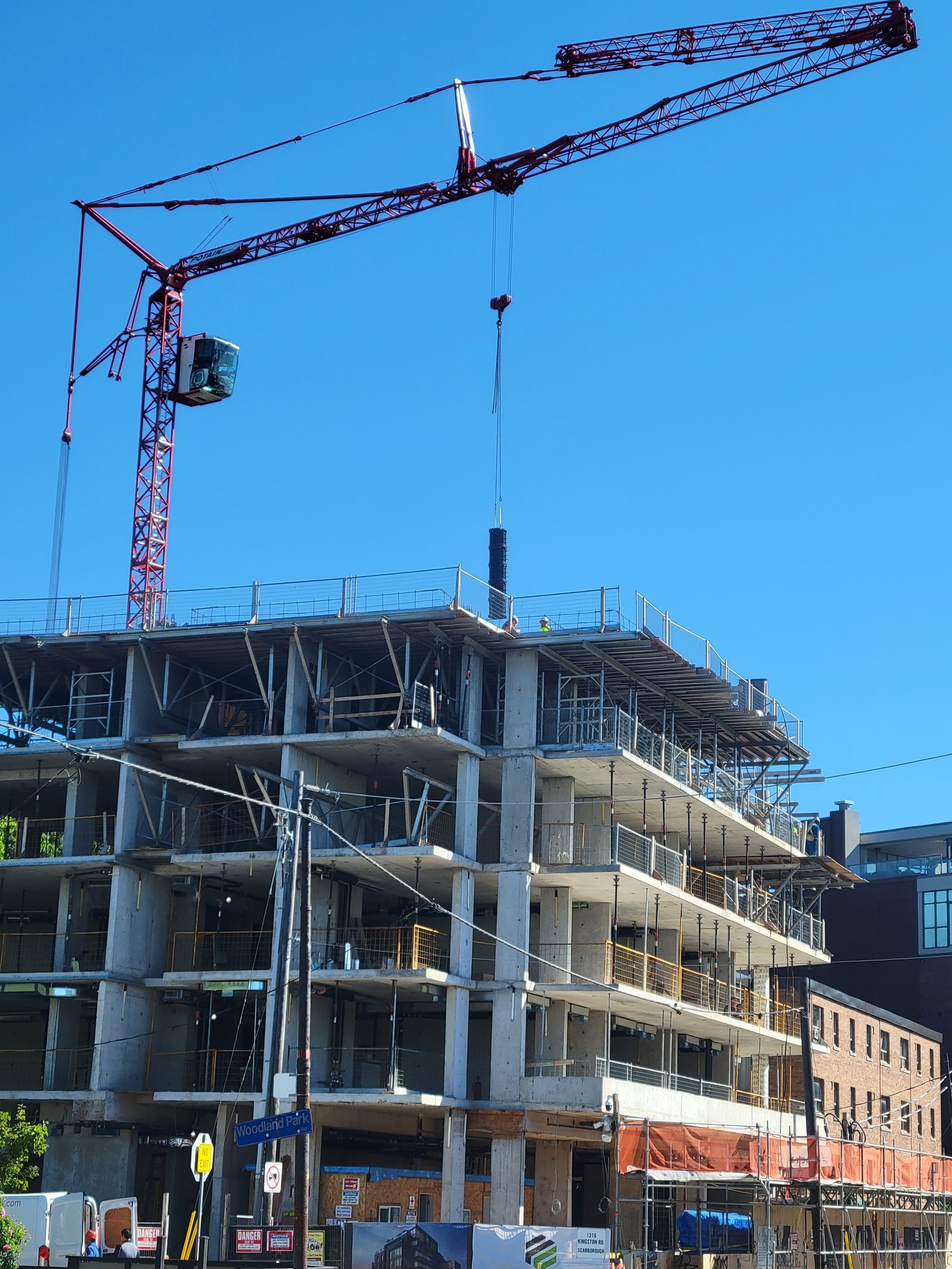 Tower crane lifting materials on a multi-storey concrete building frame in Toronto