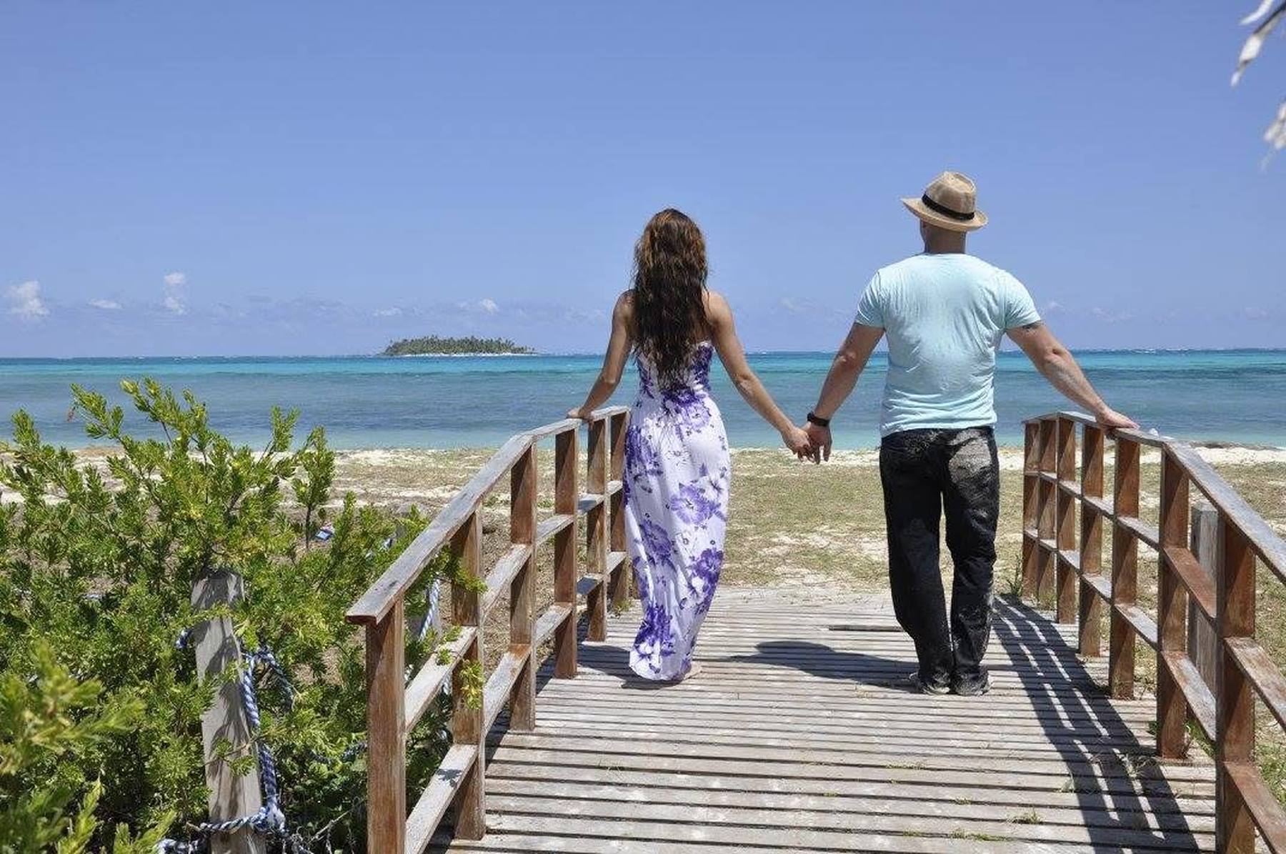 Couple walking hand in hand toward the beach