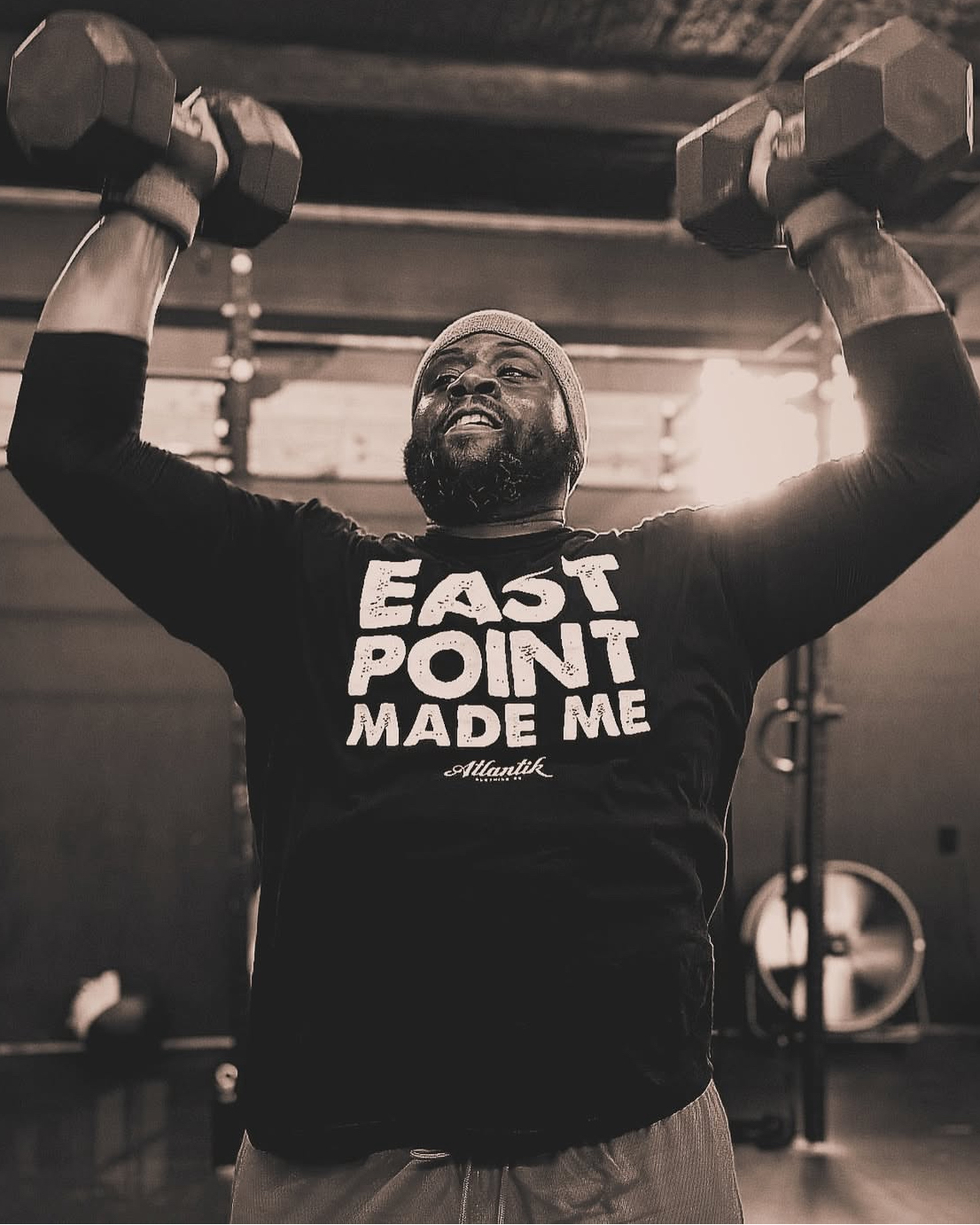 Man lifting dumbells above his head during a strenght training class at Phys. Ed. in East Point, Georgia