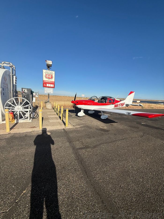 Red and white 2023 Sling LSA N6176F parked on an airport ramp next to a self-serve avgas pump