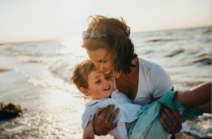 A mother and her young son at the shore, golden hour