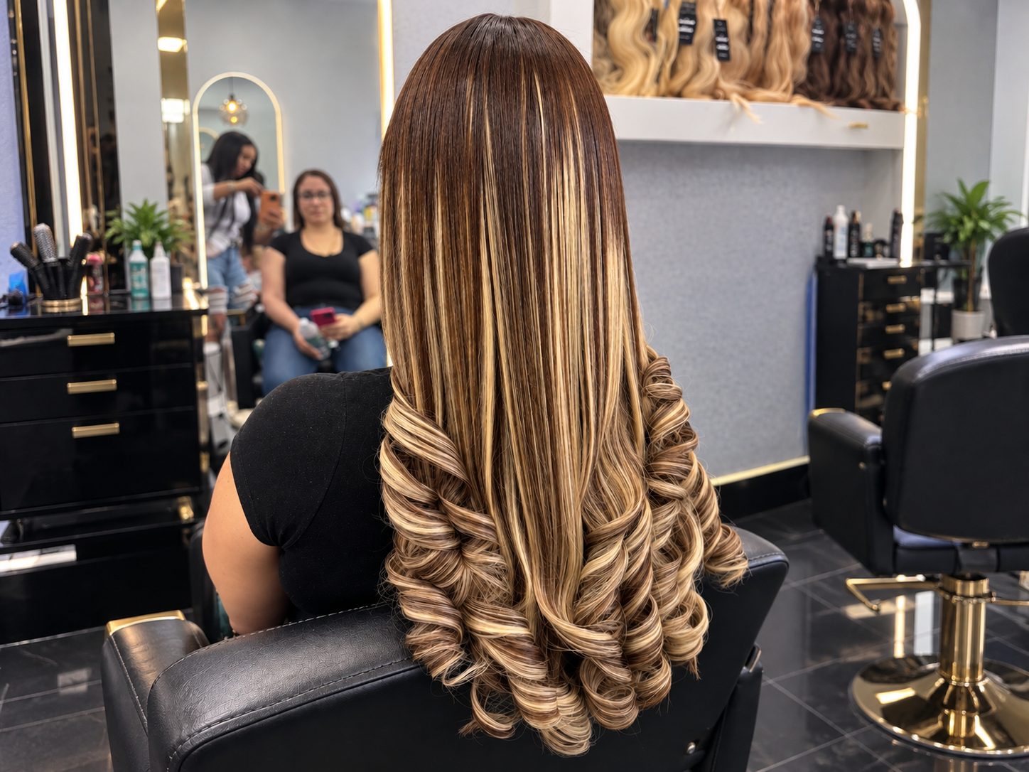 Client's long extensions with brown and blonde highlights and curled ends