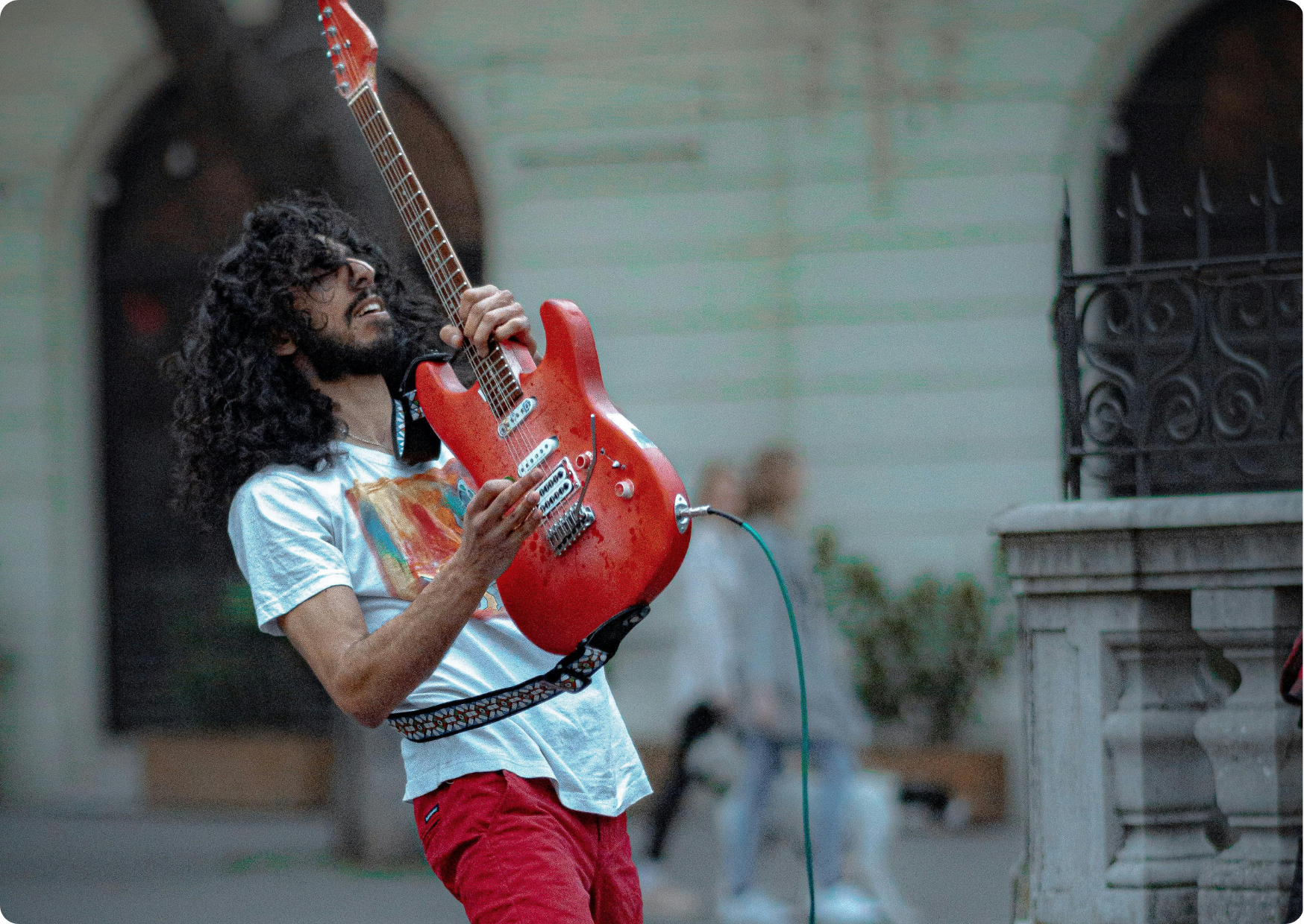 Blog Aude Compose - Musicien dans la rue avec une guitare électrique rouge levée et en jean rouge