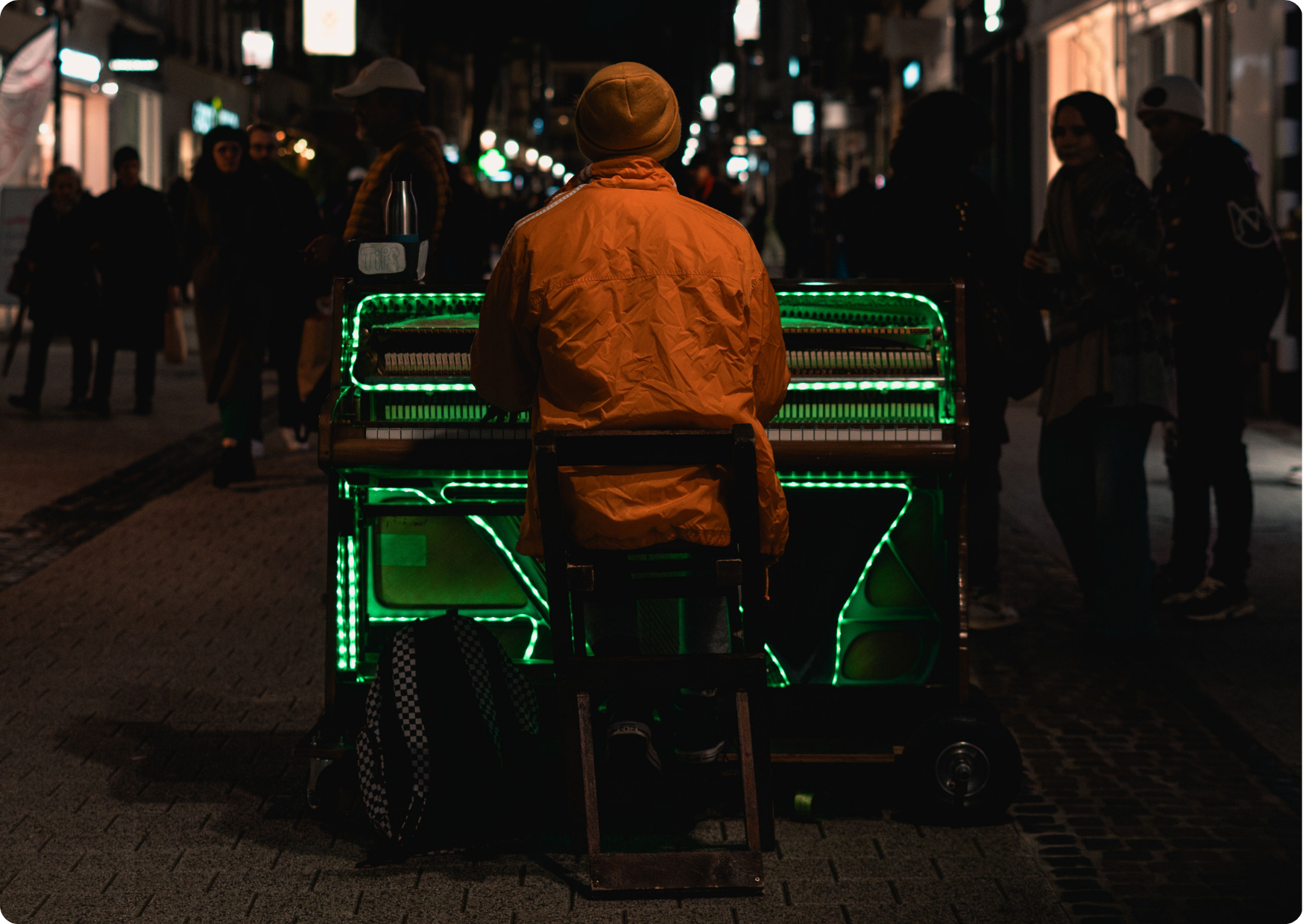 Blog Aude Compose - Pianiste avec piano et guirlande verte au milieu de la rue la nuit