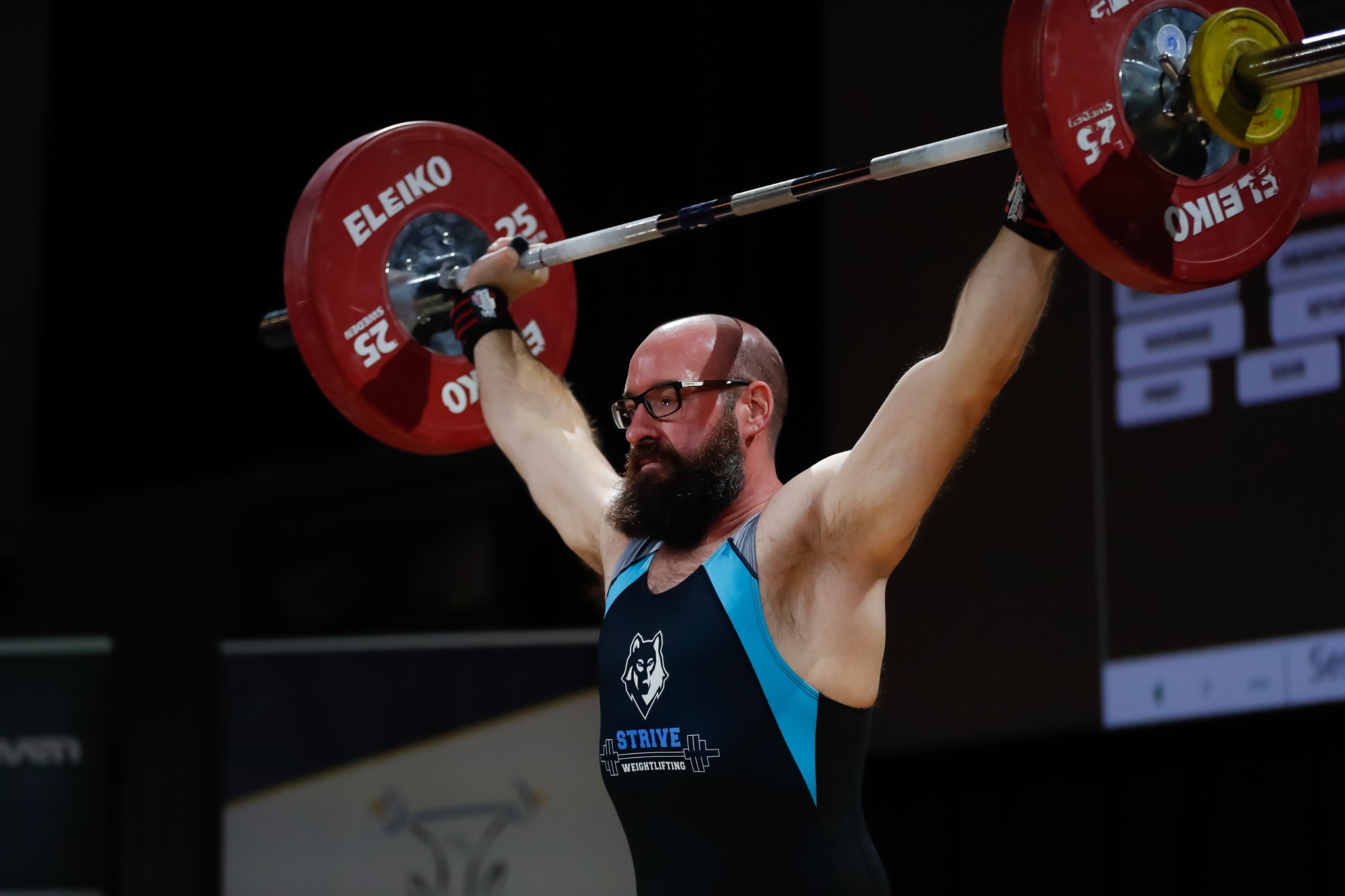 Lifter locking out a barbell overhead in competition