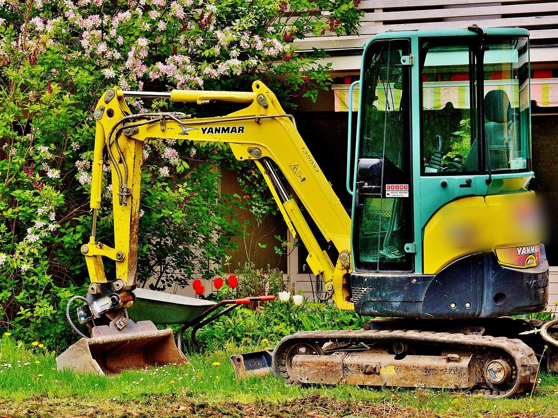 Mini-pelle dans un jardin, le type de machine louée pour arracher une souche