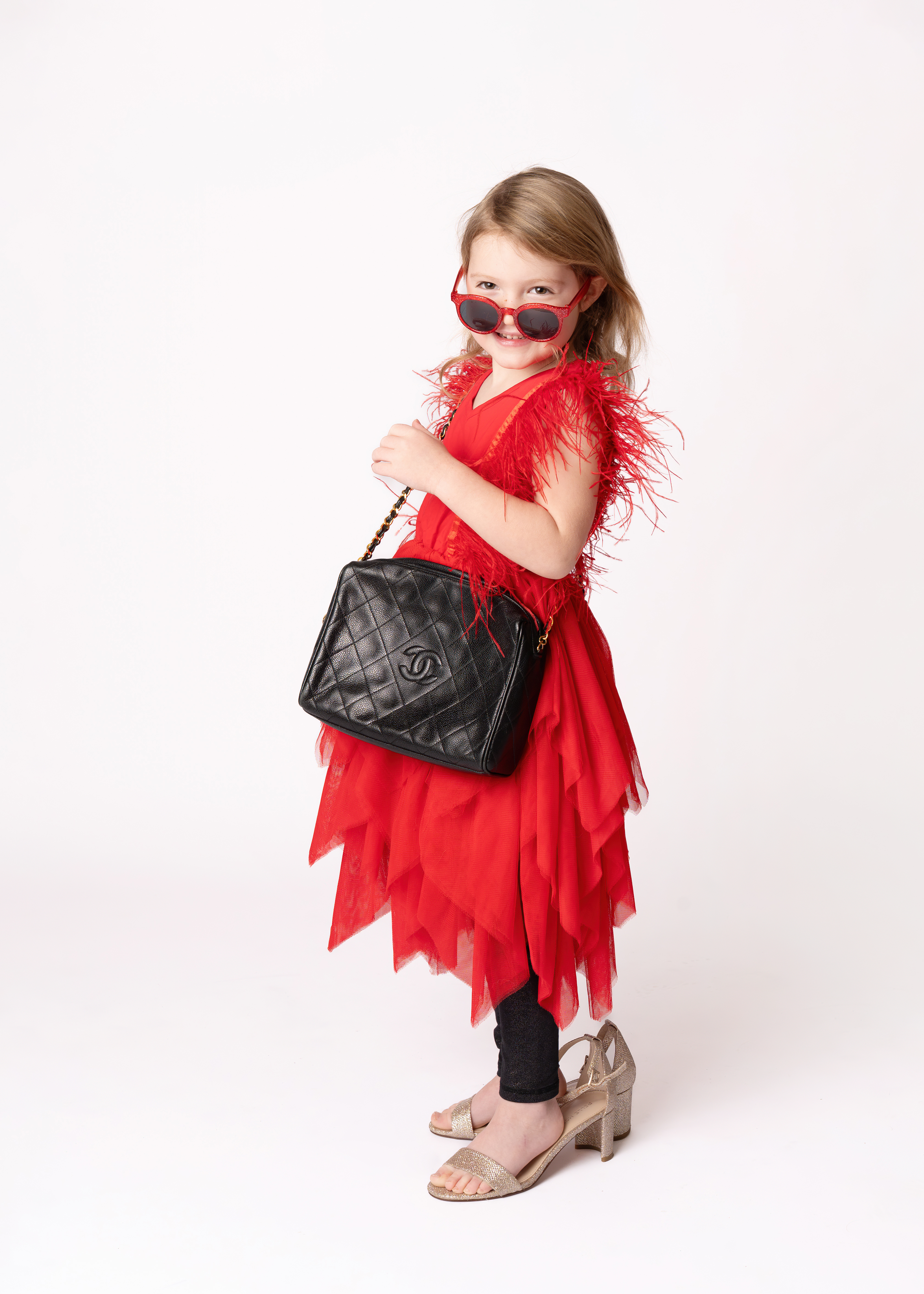 Girl in red dress with a giant purse and her moms shoes on