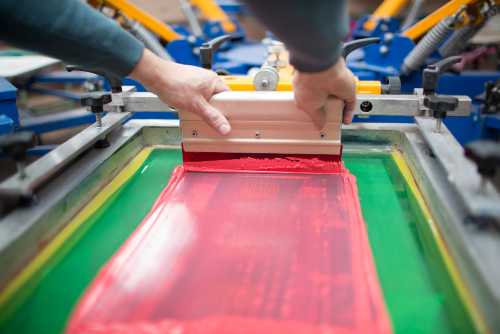 Apparel being Screen Printed with a squeege