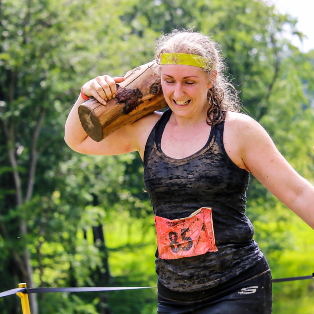 Carly carrying a log at a Total Warrior Ultra event