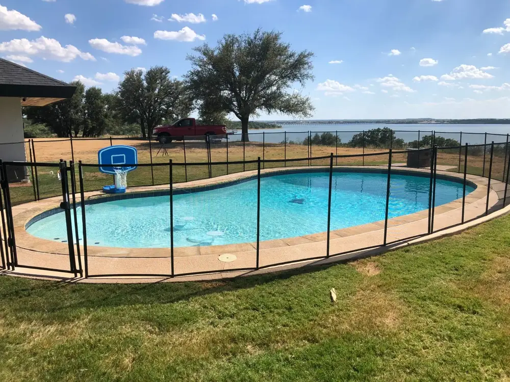 Black mesh safety fence around a backyard pool