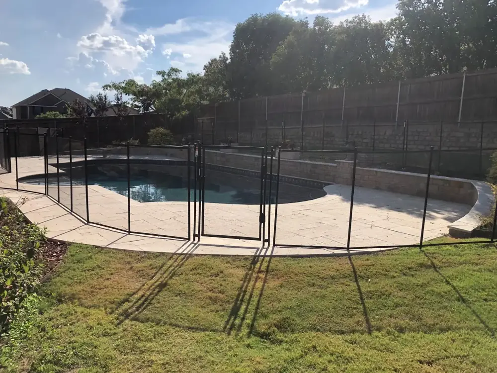 Black mesh safety fence around a backyard pool