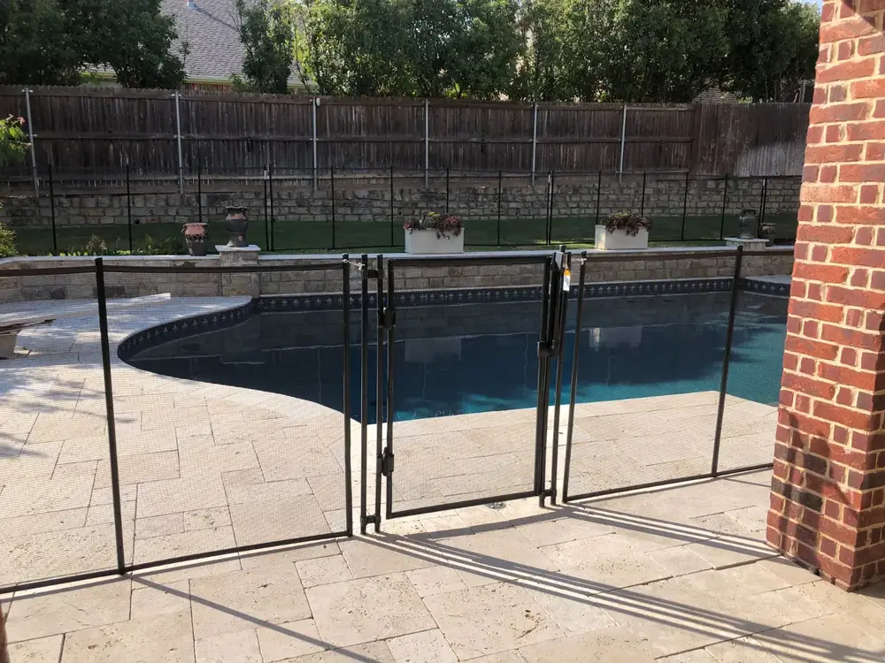 Black mesh safety fence around a backyard pool