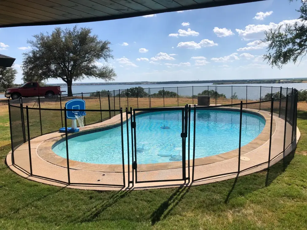 Black mesh safety fence around a backyard pool